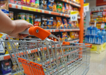 Shopping trolley cart against modern supermarket aisle blurred background