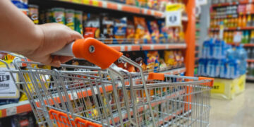 Shopping trolley cart against modern supermarket aisle blurred background